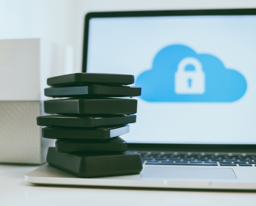 Laptop on the desk with network attached storage. Computer, nas and stack of hard drives on the table. Cloud technology, online disk, remote backup, security copy and archiving internet concept.